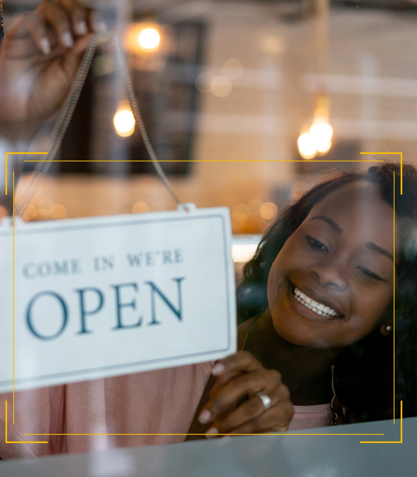 A happy small business owner with an open store sign