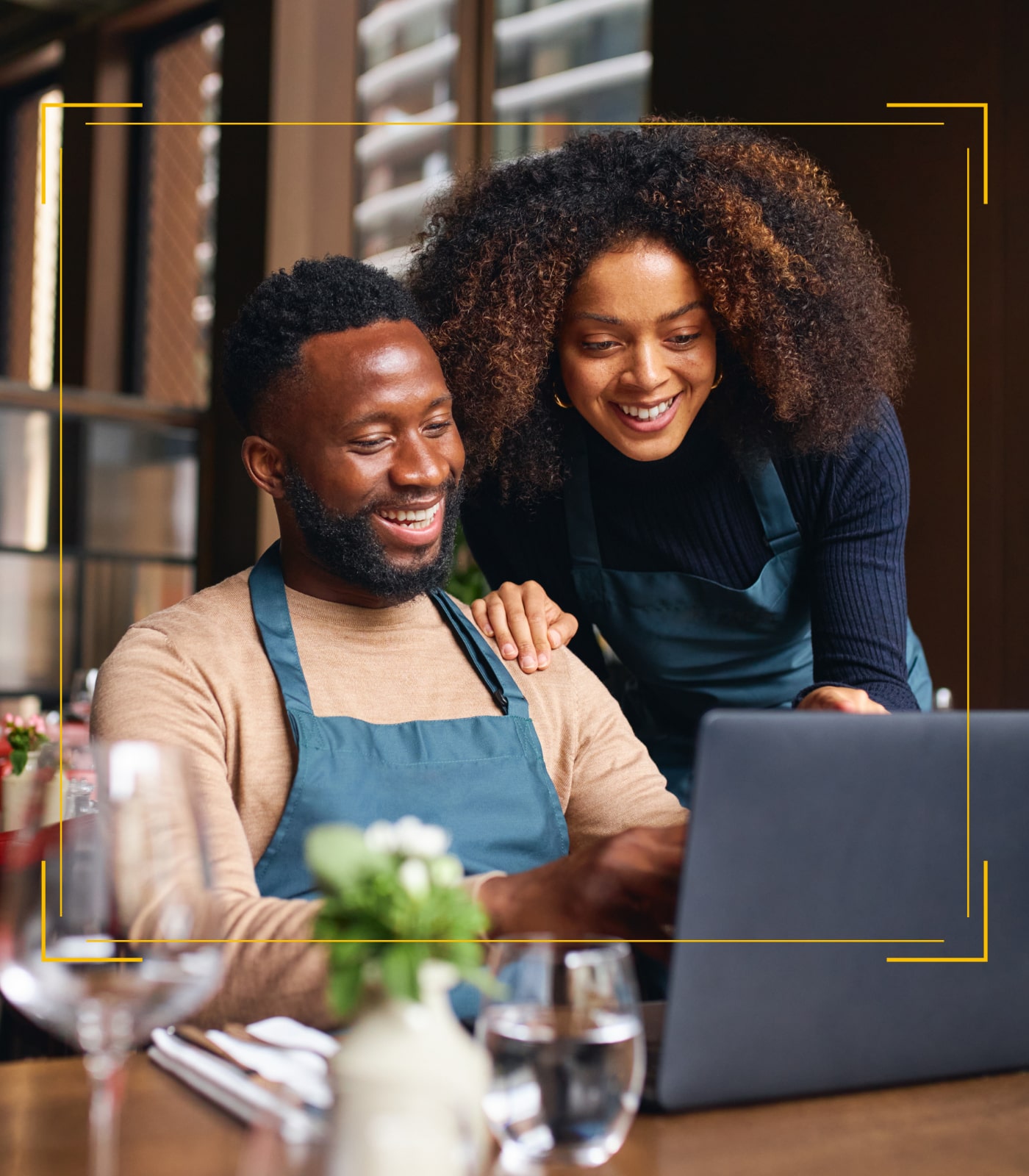 Two people leaning over a table using a laptop